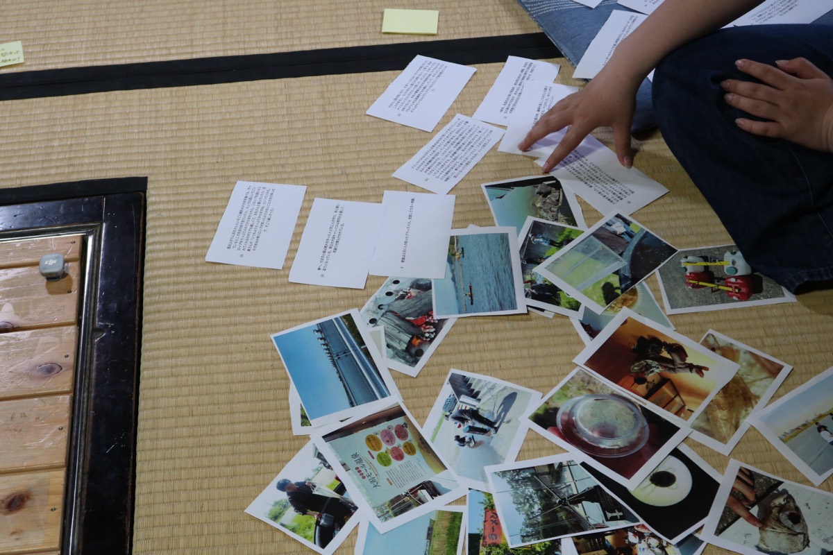 参加者が畳に広がった写真カードの中から1枚を選んでいる